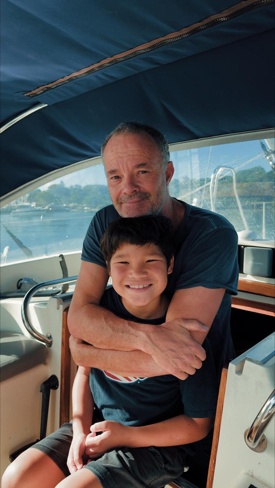 A father and son embracing aboard a boat, sunlit cabin