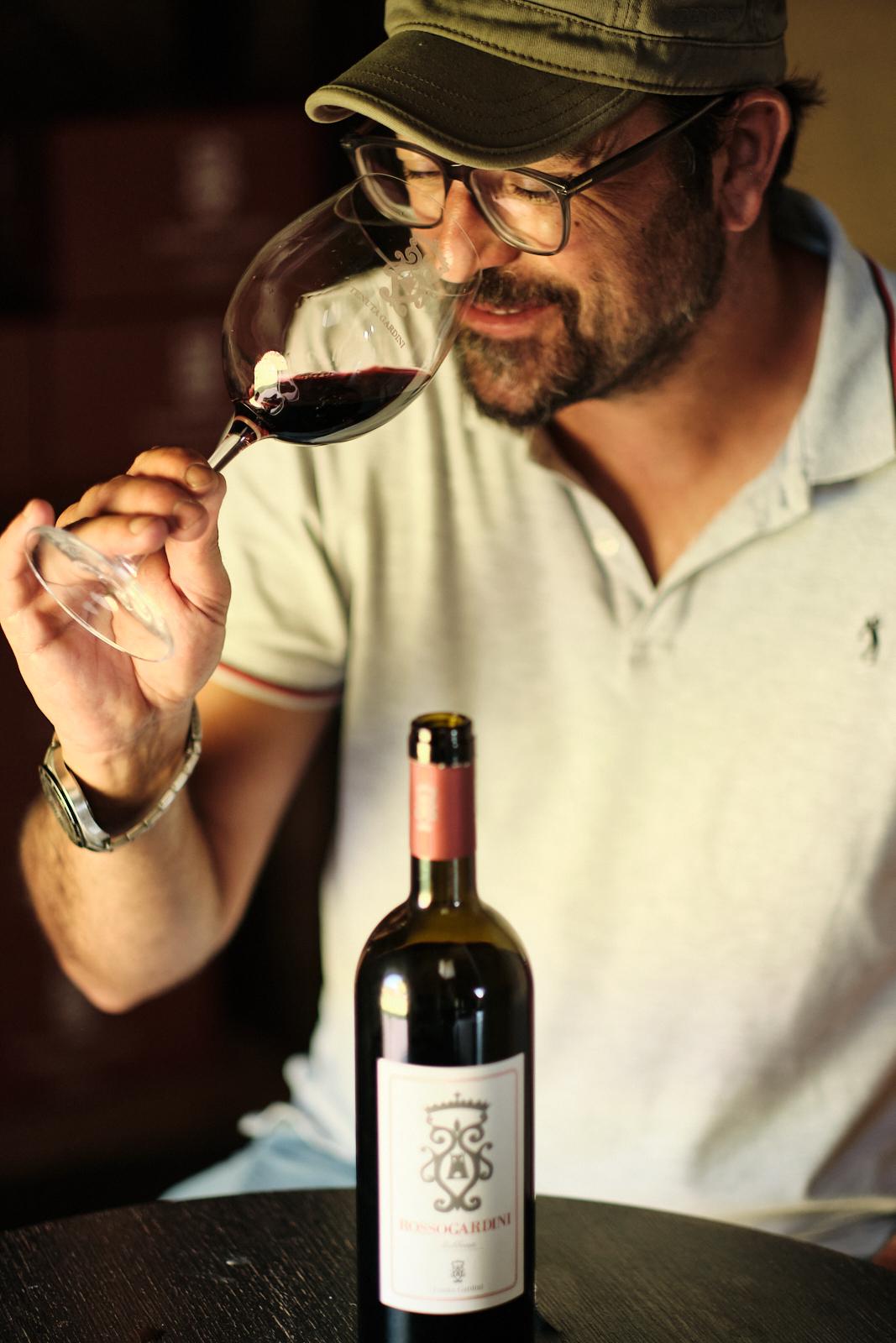 A guest smelling a glass of red wine at a tasting, bottle on the table
