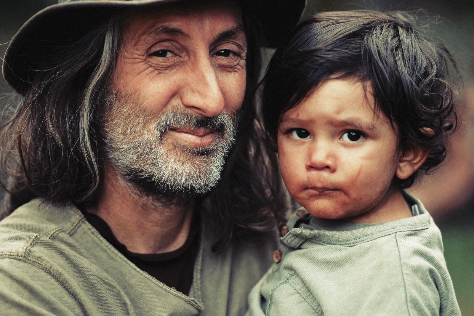 A festival-goer holding a child close, both looking at the camera