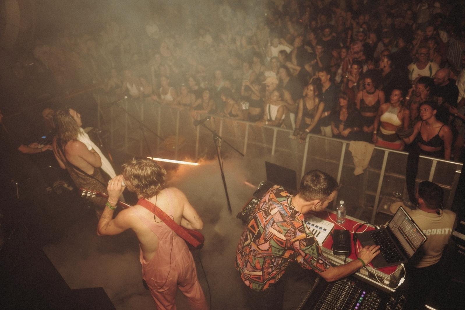 View from the stage over a barrier into the crowd, smoke and stage light