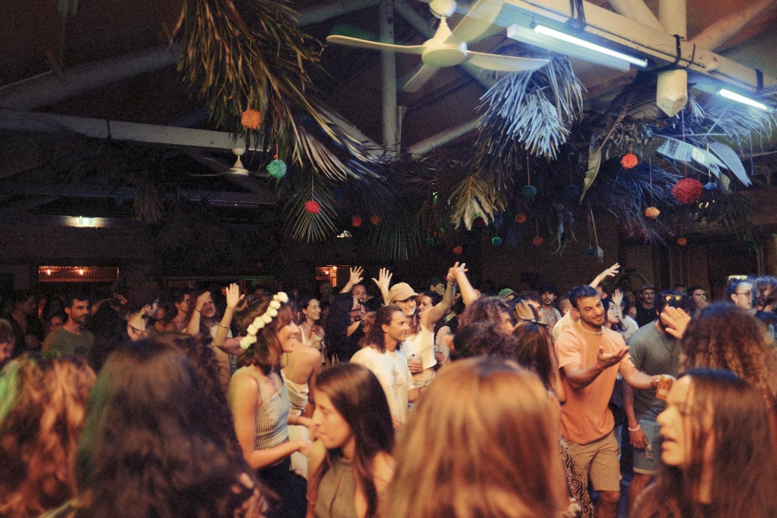 Dancefloor beneath palm fronds and hanging pompoms