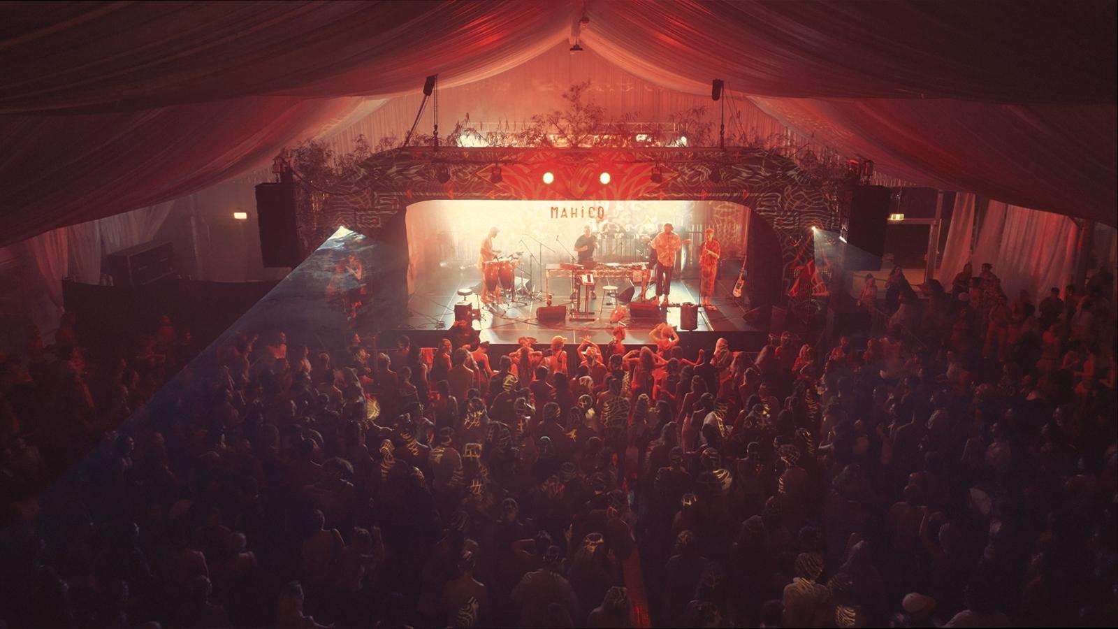 A packed marquee dancing in front of the Mahico stage, red lighting