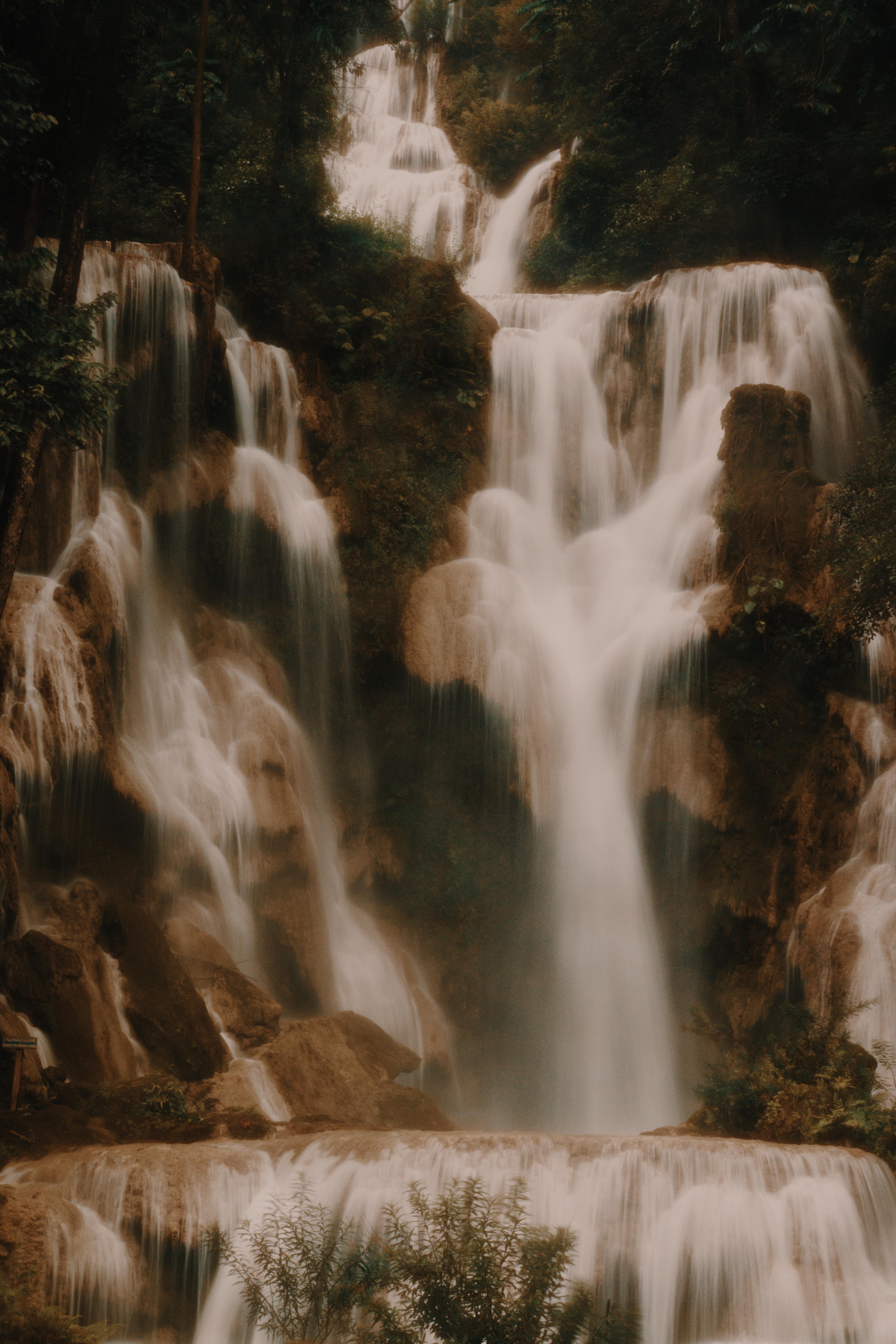 A tiered waterfall cascading over limestone terraces through the forest