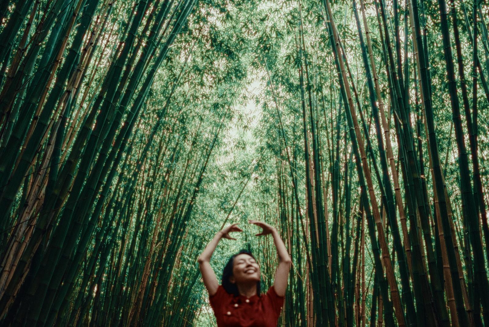 Suya laughing with her arms raised inside a bamboo grove