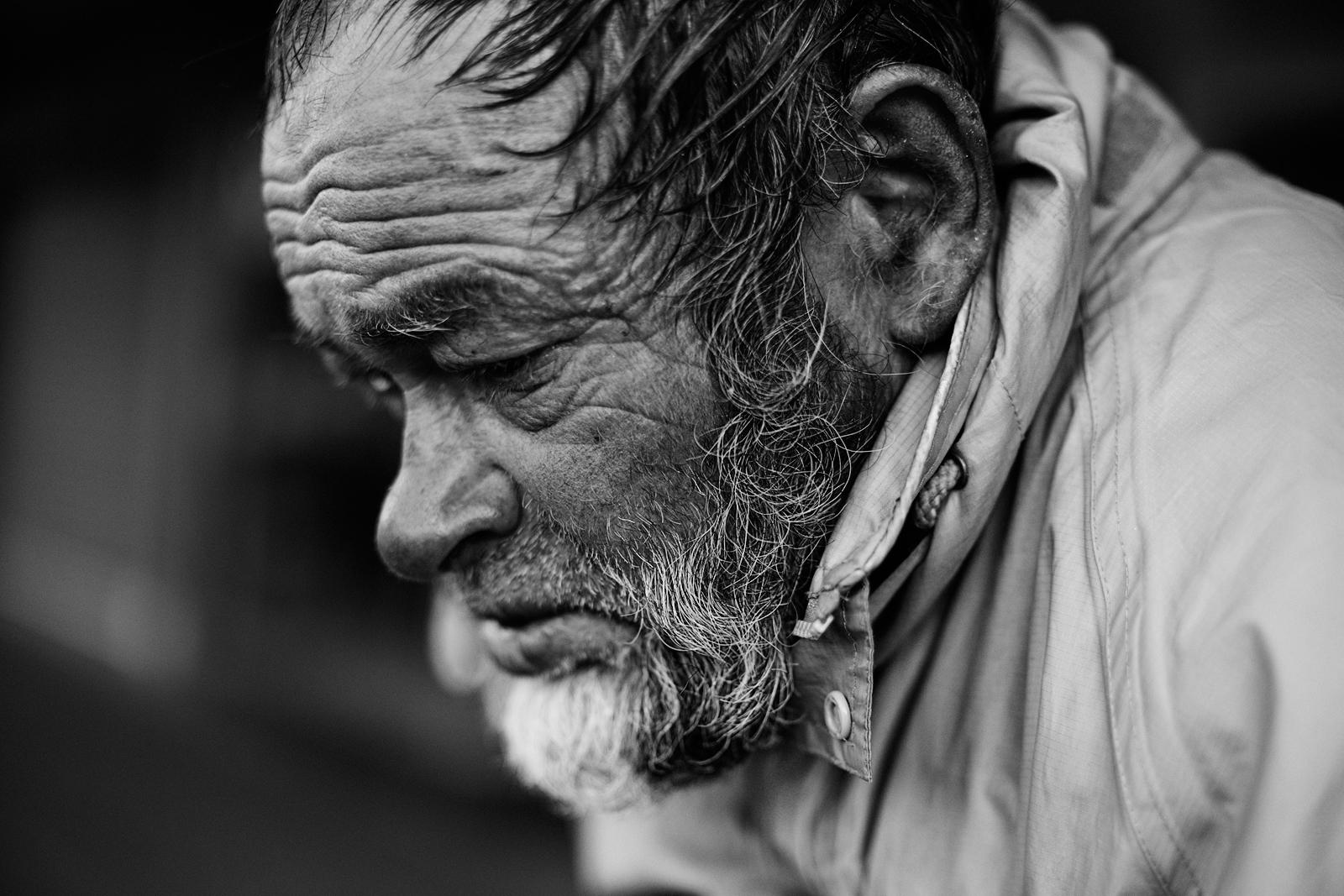 Black and white close-up of the same man's weathered forehead and beard, eyes lowered