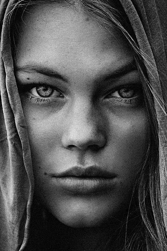 Close portrait of a young woman in a hood, direct gaze, black and white
