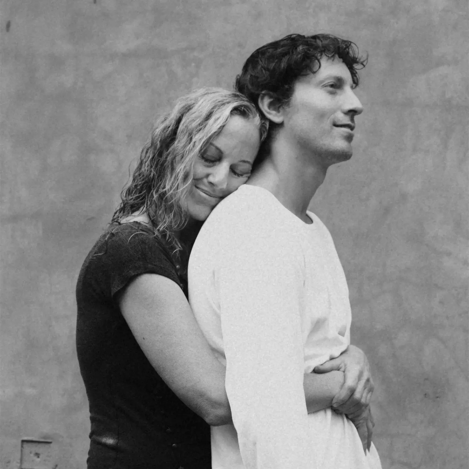 A mother resting her head on her son's shoulder, studio black and white portrait