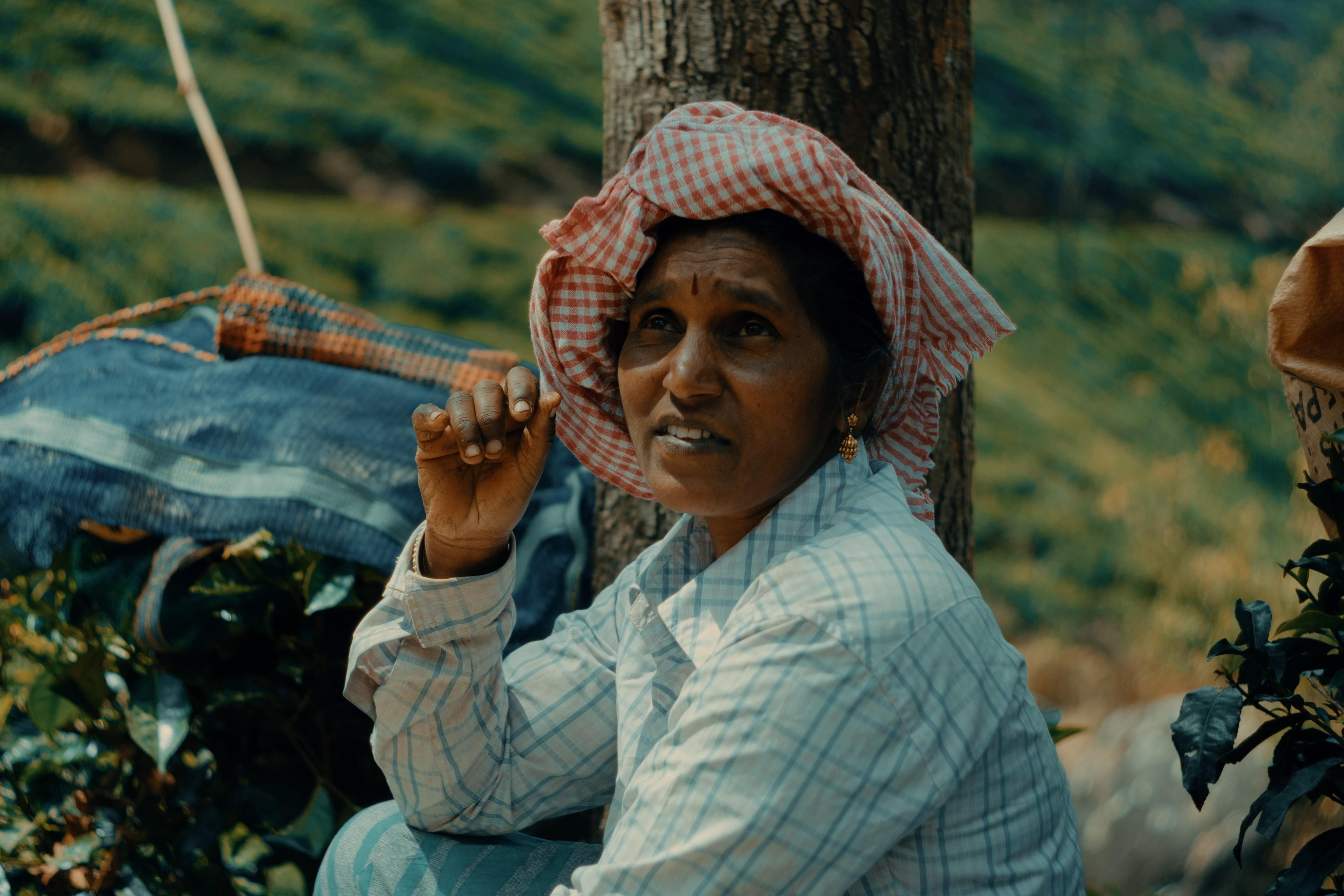 A picker adjusting her headscarf mid-conversation, hand raised