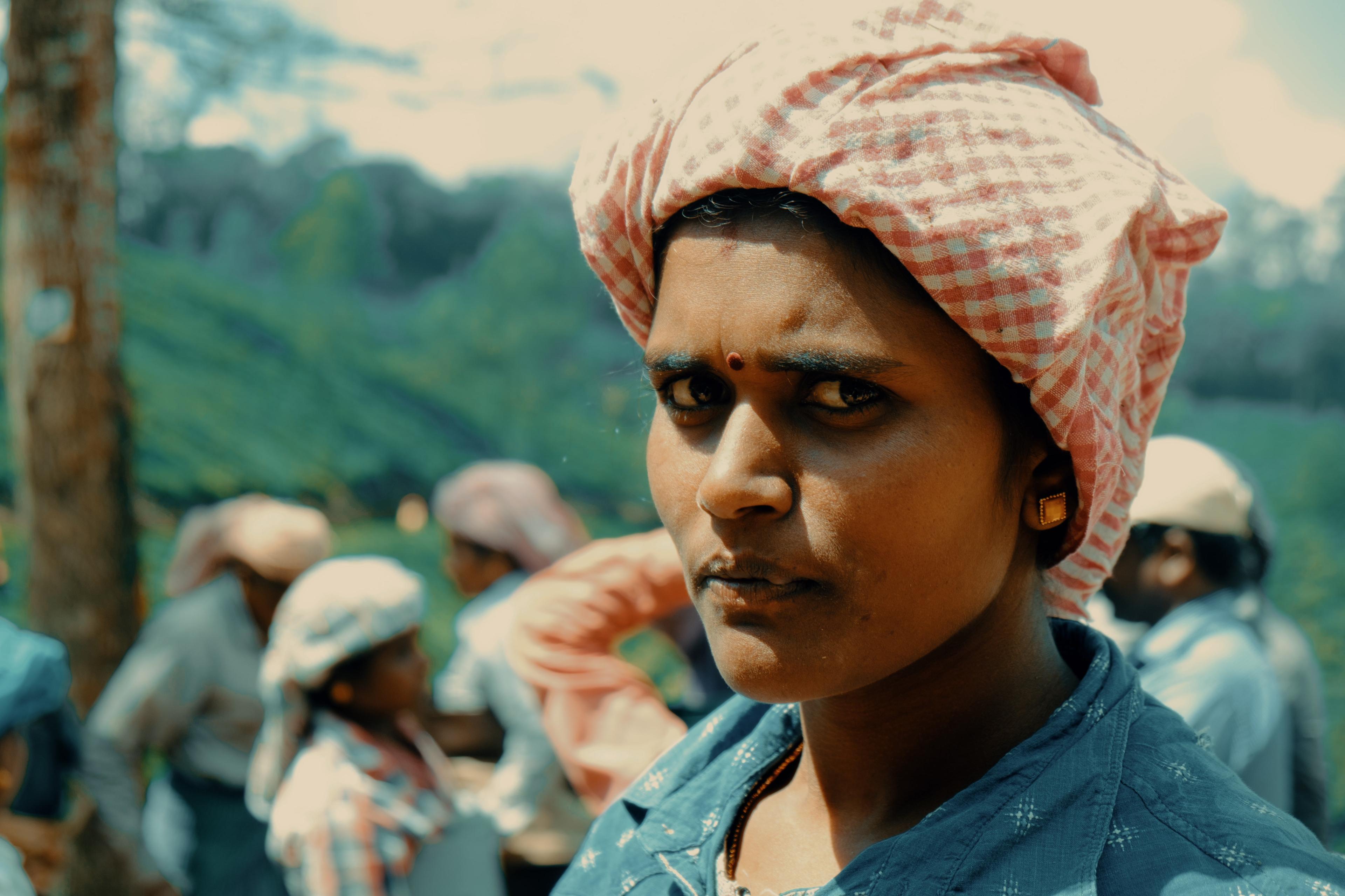 Close portrait of a picker in a checked headscarf, gold earring catching the light