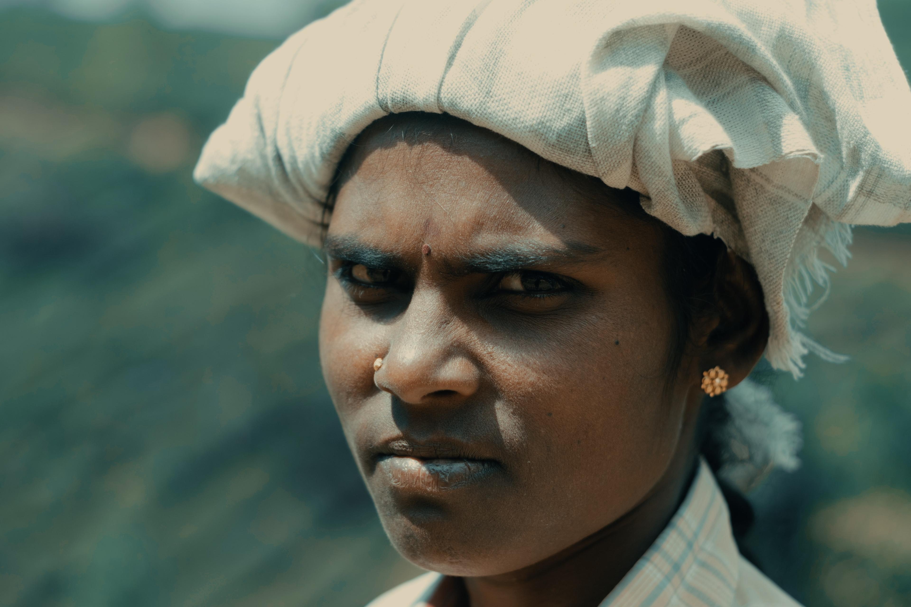 Close portrait of a picker in a cream headscarf, direct gaze