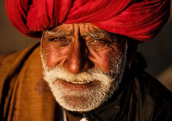 Close portrait of a man in a red turban, smiling, in Pushkar